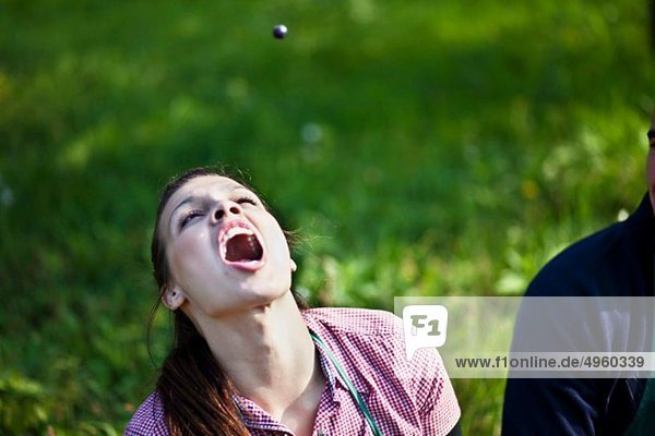 Croatia  Baranja  Young woman catching a grape with mouth open
