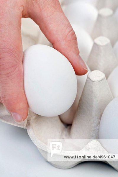 Menschliche Hand hält Ei aus Eierkarton