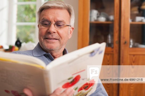 Senior Mann liest Kochbuch