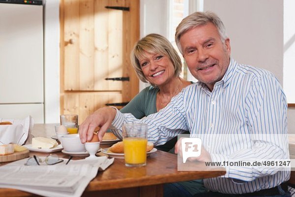 Germany  Kratzeburg  Senior couple having breakfast  smiling  portrait