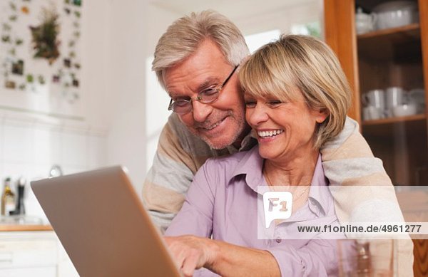 Germany  Kratzeburg  Senior couple using laptop  smiling