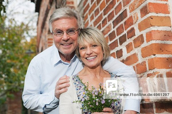 Deutschland  Kratzeburg  Seniorenpaar mit Blumenstrauß im Landhaus  lächelnd  Portrait