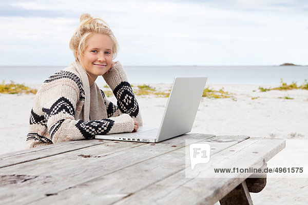 Teenage girl sitting at table  using laptop