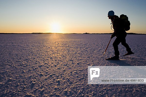 Mann Eislaufen auf Schnee bedeckt Landschaft in der Dämmerung