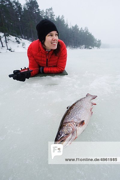 Frau Eis Fischen auf zugefrorenen See  lächelnd