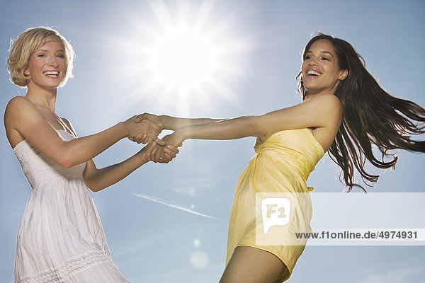 Zwei fröhliche junge Frauen unter blauem Himmel