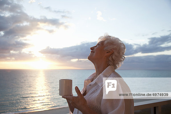 Senior Woman drinking coffee at sunrise