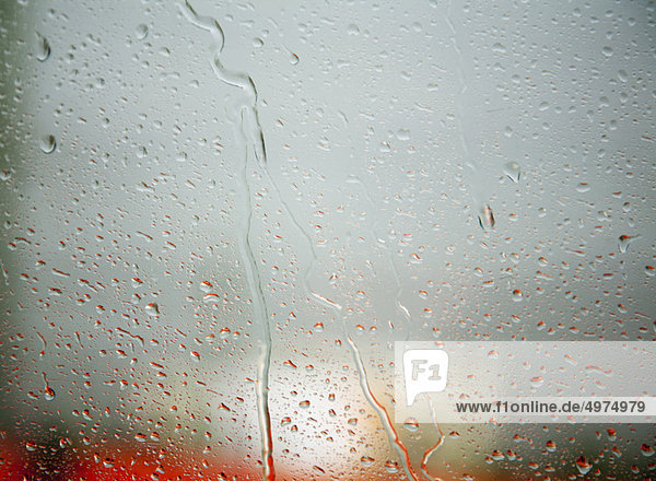 Regentropfen am Fenster roter Bus dahinter