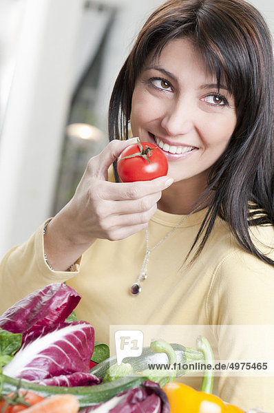 Smiling woman with tomato and vegetables