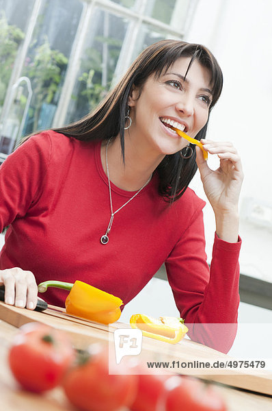 Young woman tasting fresh yellow pepper