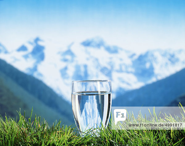 Ein Glas Wasser vor Berglandschaft