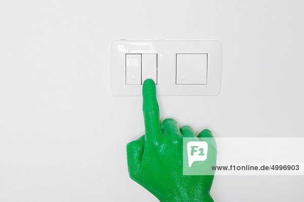 A green hand switching on a light