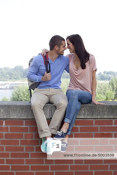 Young couple sitting on wall