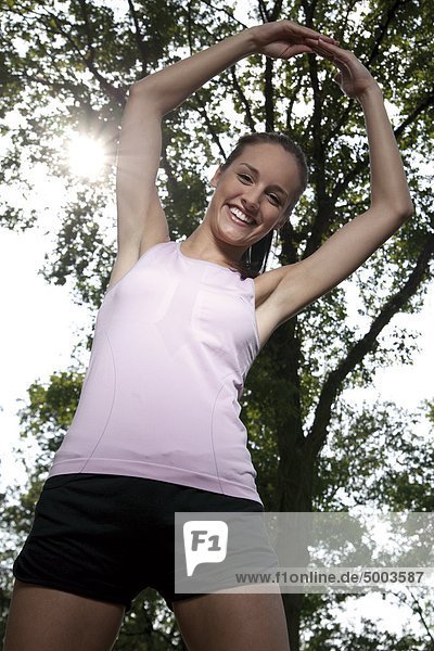 Happy young woman in sportswear at a tree