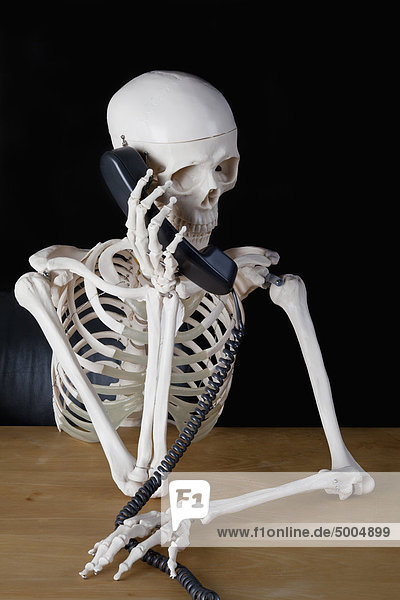 Ein Skelett mit einem Festnetztelefon