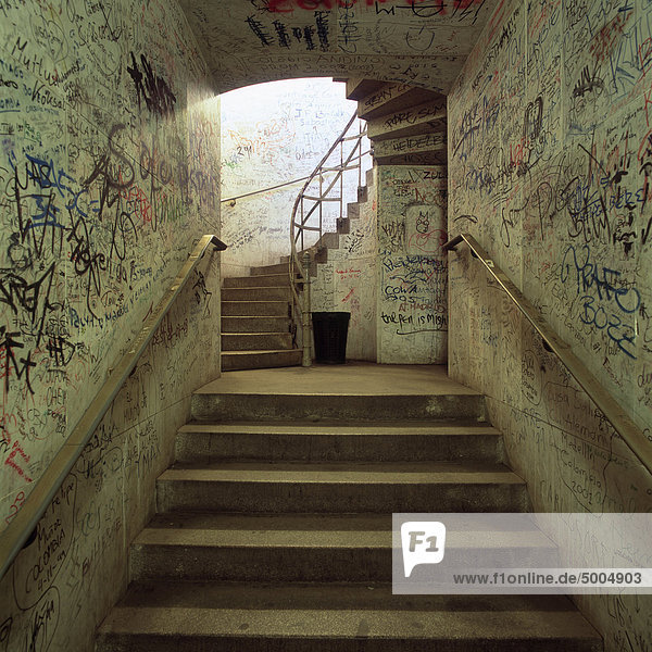 An underground stairway with graffiti on the walls
