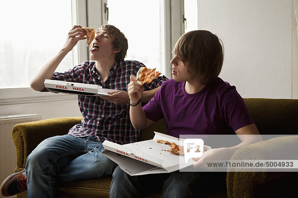 Two boys eating delivery pizza