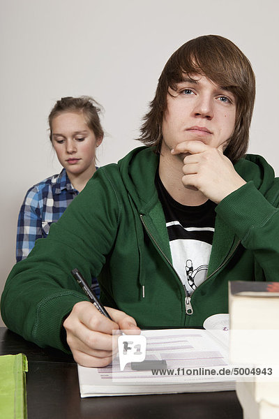 Ein Teenager denkt im Klassenzimmer  ein Mädchen im Hintergrund.