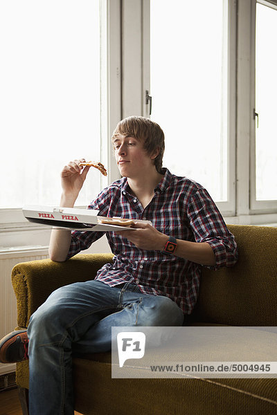 Ein Teenager  der Lieferpizza isst.