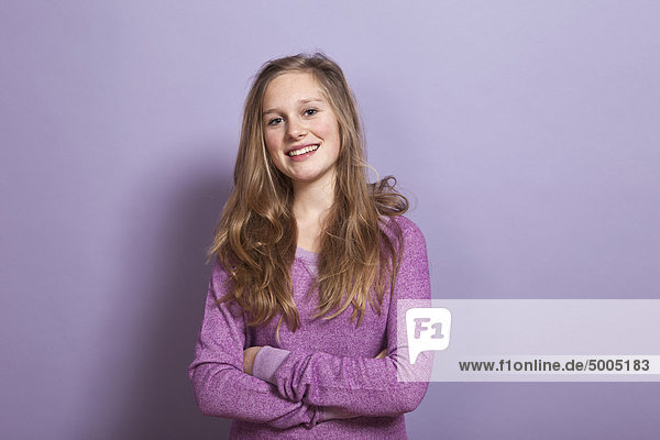 Ein lächelndes Teenagermädchen mit verschränkten Armen,  Porträt,  Studioaufnahme