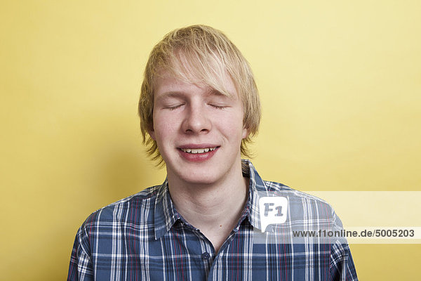 Ein lächelnder Teenager mit geschlossenen Augen,  Porträt,  Studioaufnahme