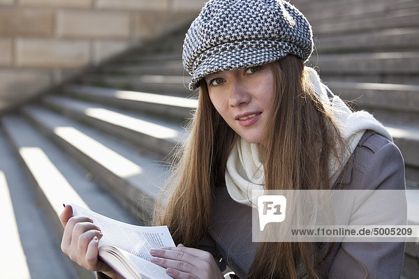 Woman on steps outside reading