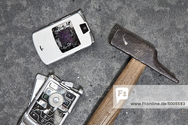 Ein zerschmettertes Handy und ein Hammer.