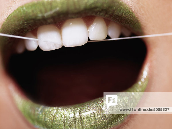Eine Frau  die ihre Zähne mit Zahnseide pflegt  extrem nah am Mund  Mund.