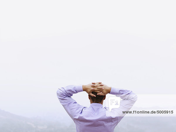 A businessman with his hands behind his head looking at the view  outdoors