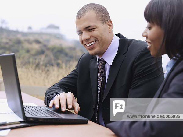 Ein Geschäftsmann und eine Geschäftsfrau  die zusammen einen Laptop benutzen.