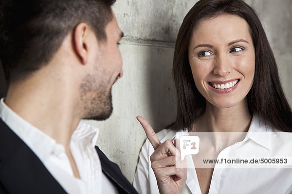 A smiling businesswoman scolding a businessman