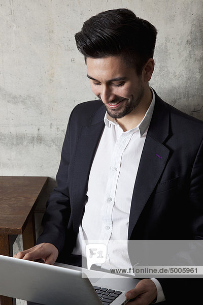 A smiling businessman working on a laptop  high angle view