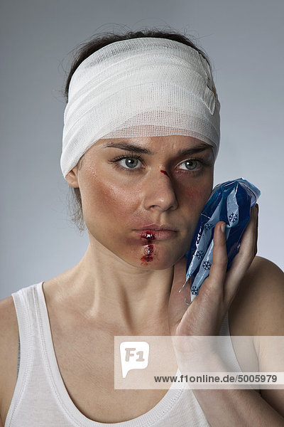 Eine Frau mit blauen Flecken und einem bandagierten Kopf.