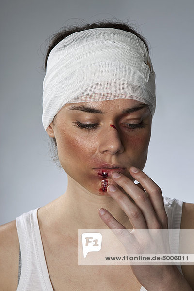 Eine Frau mit Verletzungen und einem bandagierten Kopf und Mund.