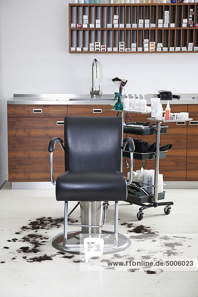 An empty barber chair with cut hair around it