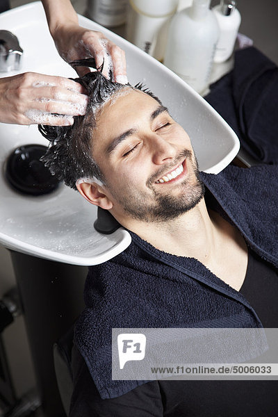 Ein Mann  der seine Haare in einem Friseursalon waschen lässt.