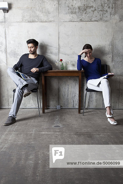 A couple ignoring each other while reading separate magazines