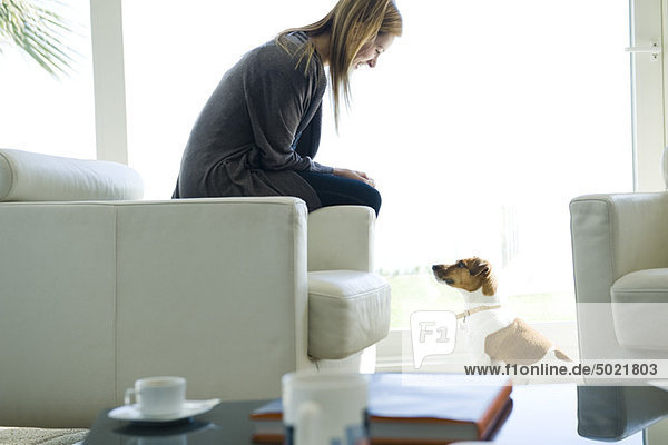 Frau entspannt im Wohnzimmer mit Hund