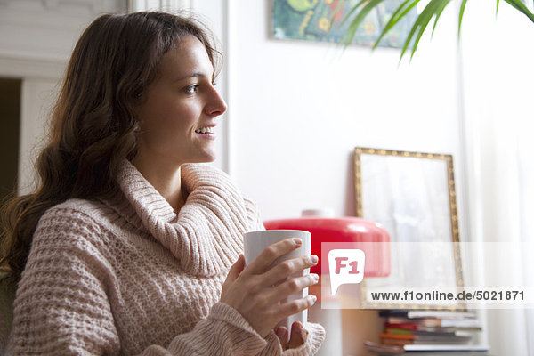 Young woman enjoying cup of coffee at home