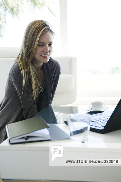 Woman using laptop computer at coffee table