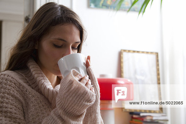 Junge Frau genießt zu Hause eine Tasse Kaffee