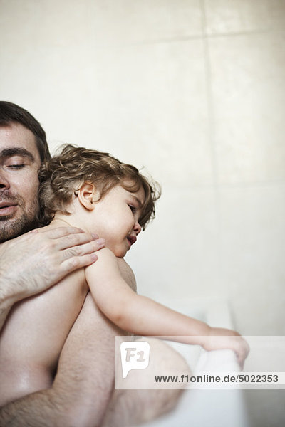 Vater tröstet weinenden Sohn im Bad