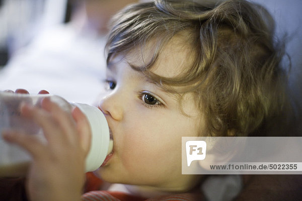 Kleinkind Junge trinkt Milch aus der Babyflasche