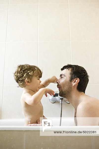 Vater und Kleinkind spielen zusammen im Bad
