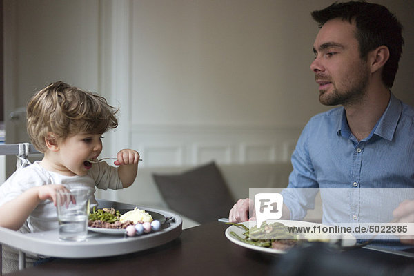 Father and toddler son eating dinner together