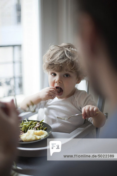 Kleinkind Junge beim Essen  Blick auf die Eltern im Vordergrund