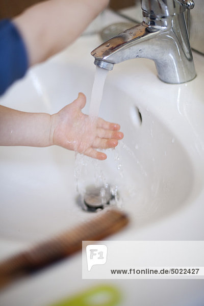 Child washing hands in sink
