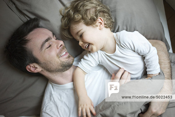 Father and young son relaxing together in bed  portrait