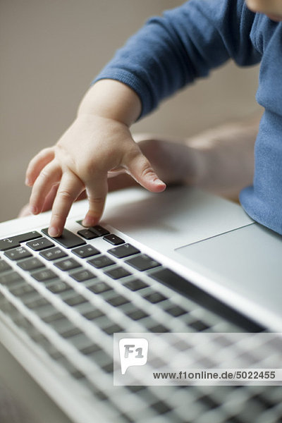 Child's hand touching laptop keyboard