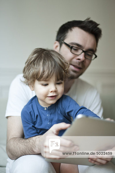 Father and young son looking at digital tablet together